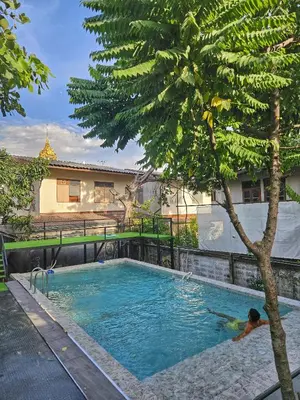 a person in a swimming pool next to a tree at Here Hostel Bangkok in Bangkok