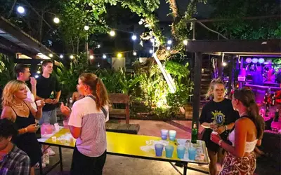 a group of people standing around a table with drinks at Here Hostel Bangkok in Bangkok