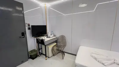 a white room with a bed and a desk with a television at Golden Mango home hotel \u91d1\u8292\u679c\u4e4b\u5bb6\u9152\u5e97 in Bangkok