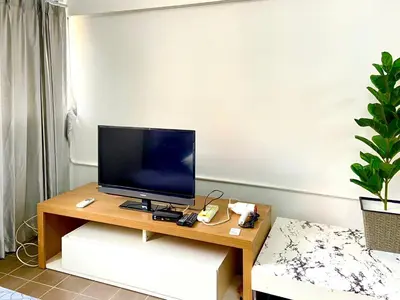 a living room with a television on a wooden table at Impact Arena Condo 2Rooms C3 by GoodRoom24 in Ban Bang Phang