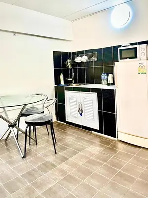 a kitchen with a table and a chair and a refrigerator at Impact Arena Condo 2Rooms C3 by GoodRoom24 in Ban Bang Phang