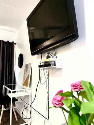 a flat screen tv hanging on a wall with a plant at Impact Arena Condo C3 Grey by GoodRoom24 in Ban Bang Phang