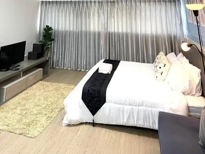 a bedroom with a white bed and a flat screen tv at Impact Arena Condo TwoTone By GoodRoom24 in Ban Song Hong