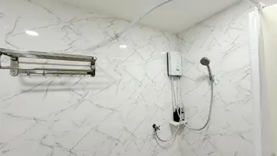 a white marble wall with a shower in a bathroom at Issara House Bangkok in Bangkok