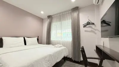 a white bedroom with a bed and a window at Issara House Bangkok in Bangkok