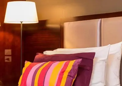 a lamp sitting next to a bed with pillows at Ratchada Point Hotel in Bangkok