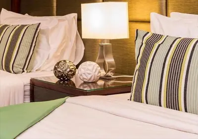 a bedroom with two beds and a lamp on a night stand at Ratchada Point Hotel in Bangkok