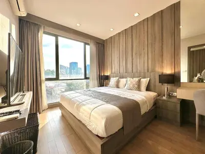 a bedroom with a large bed and a large window at Cozy & Bright apartment - Asoke in Bangkok
