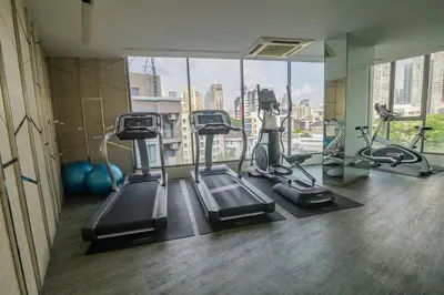 a gym with three tread machines and a large window at Cozy & Bright apartment - Asoke in Bangkok