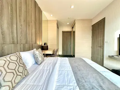 a bedroom with a large bed and a desk at Cozy & Bright apartment - Asoke in Bangkok
