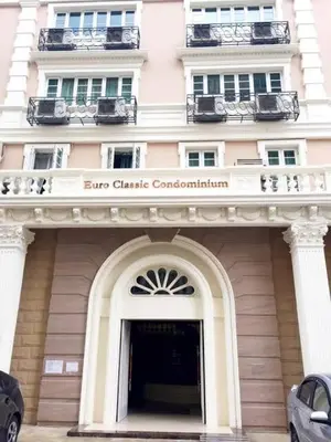 a large pink building with a sign above a doorway at Euro Classic Condominium in Bangkok
