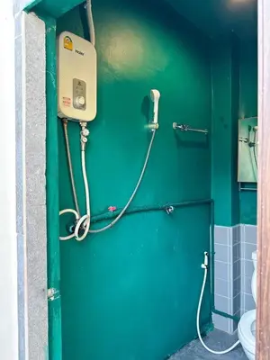 a bathroom with a green wall and a toilet at Shared Room Megun in Ban Bang Phlat