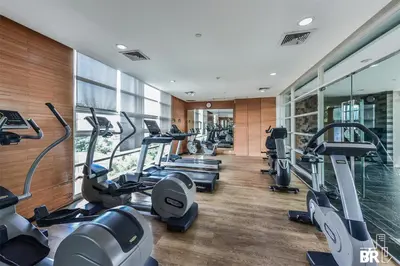 a gym with a row of treadmills and elliptical machines at Watermark Chaophraya River Condo in Bangkok