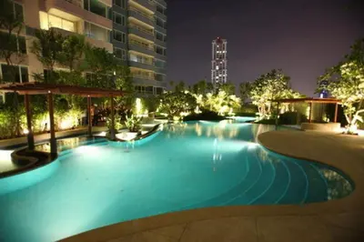 a large swimming pool at night with a building at Watermark Chaophraya River Condo in Bangkok