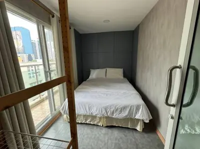 a small bedroom with a bed and a window at Near Big Jodd Fair Night Market and Shopping Mall in Bangkok