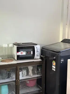 a microwave sitting next to a small refrigerator at J House in Nonthaburi