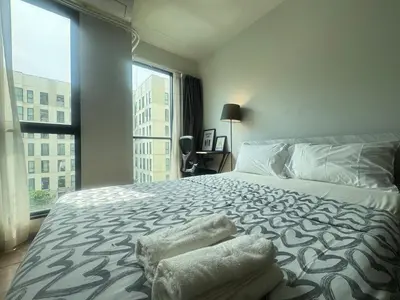 a bedroom with a large bed and a large window at Sunlit Nest Sukhumvit in Ban Khlong Samrong