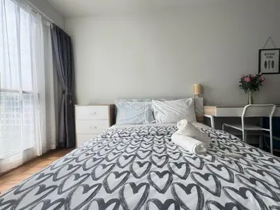 a bedroom with a black and white bed with a desk at Sunlit Nest Sukhumvit in Ban Khlong Samrong