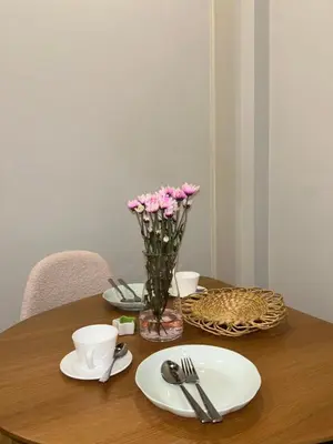 a wooden table with plates and a vase of pink flowers at Mookda House Chinatown BKK near MRT Samyot in Khlong San