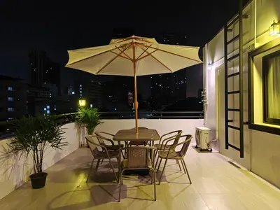 a table and chairs with an umbrella on a balcony at Thonglor 4-story modern art villa Free WiFi Netflix in Bangkok