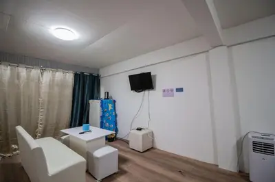 a living room with a white chair and a tv at Skutan-MTB Bangchak in Bangkok