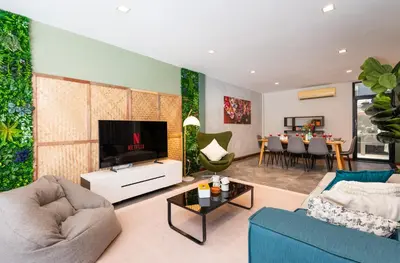 a living room with a blue couch and a tv at 3BR design townhouse in central Bangkok - 10min to BTS, Emquartier in Bangkok