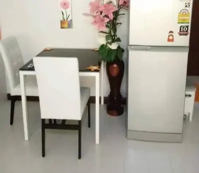 a table with two chairs and a vase with flowers at Popular Condo เมืองทองธานี in Thung Si Kan