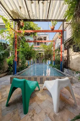 a courtyard with two white and green chairs in front of a pool at The Anonymous House in Bangkok