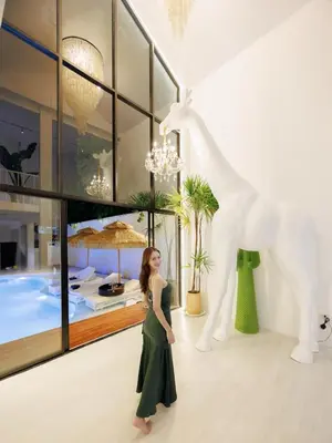 a woman in a green dress standing in front of a giraffe at Fira\u5e7d\u58837\u5367\u6cf3\u6c60\u8c6a\u534e\u522b\u5885 in Sathani Khlong Tan