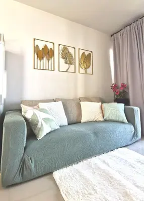 a living room with a green couch with pillows at PERFECT 80sqm apartment serve up to 5 \u5b8c\u7f8e\u7684\u516c\u5bd3 in Bangkok
