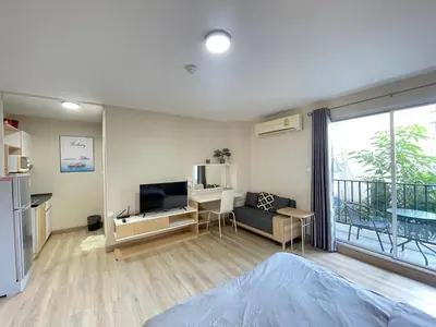 a living room with a couch and a television and a balcony at Studio16 at Changwattana in Ban Bang Phang