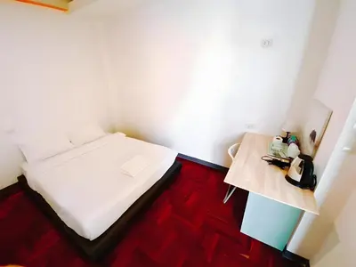 a small room with a bed and a table at XX GO INN Silom BTS Surasak - สุรศักดิ์ in Bangkok