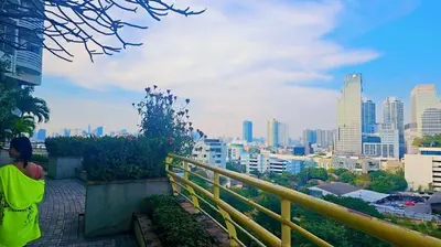 a person sitting on a ledge looking at a city at River View Active 6 in Bangkok