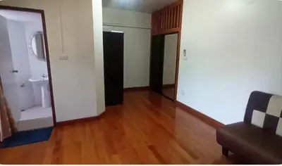 a living room with a couch and a wooden floor at Rachaprorob condo in Bangkok