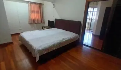 a bedroom with a bed and a wooden floor at Rachaprorob condo in Bangkok