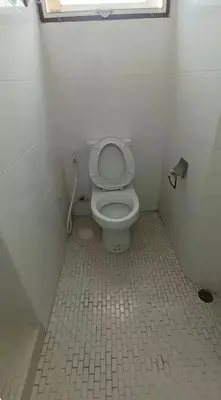 a bathroom with a toilet in a white room at Rachaprorob condo in Bangkok