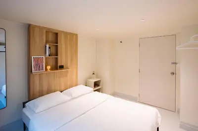 a bedroom with a white bed and a wooden cabinet at Liver Bird Ratchada in Bangkok