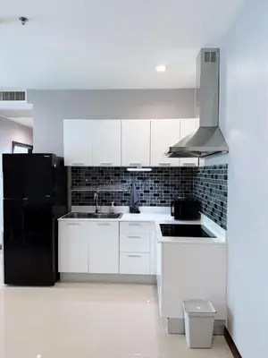 a kitchen with white cabinets and a black refrigerator at The Prime 11 Sukhumvit 11 2BR near BTS Nana in Bangkok