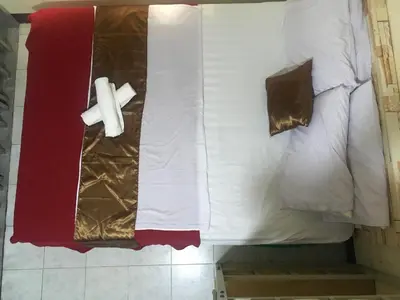 a bed with white sheets and a tie on it at Hostel 24 in Bangkok