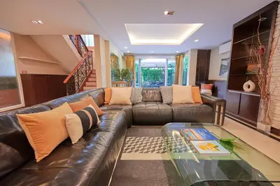 a living room with a leather couch and a glass table at Low-Rise House for Groups Near BTS & EmDistrict For Spacious Cozy Stay in Bangkok