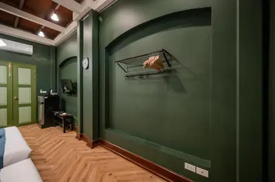 a green room with a bed and a green wall at Arun Sa Wad - Yaowarat 27 in Bangkok