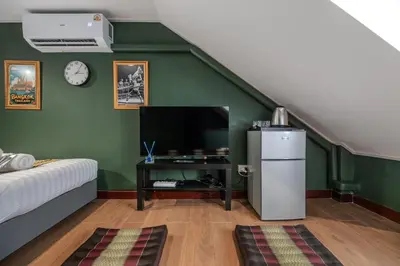 a green room with a refrigerator and a tv at Arun Sa Wad - Yaowarat 27 in Bangkok