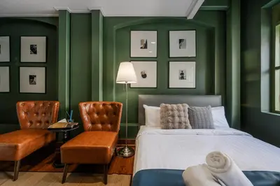 a bedroom with green walls and a bed and two chairs at Arun Sa Wad - Yaowarat 27 in Bangkok