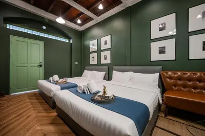 two beds in a room with green walls at Arun Sa Wad - Yaowarat 27 in Bangkok