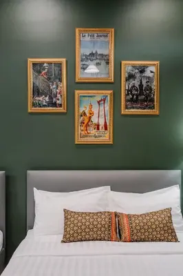 a bedroom with four pictures on a green wall at Arun Sa Wad - Yaowarat 27 in Bangkok