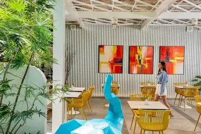 a woman standing in a restaurant with tables and chairs at Hotel Bangkokian in Bangkok