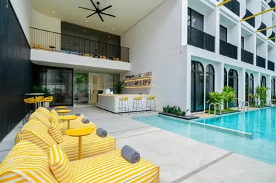 a hotel swimming pool with yellow and white striped furniture at Hotel Bangkokian in Bangkok