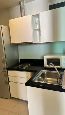 a kitchen with a sink and a microwave at Spacious Sukhumvit Condo near EmQuartier in Bangkok