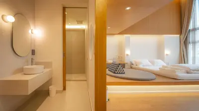 a bathroom with a bed and a sink in a room at Vaeh Viean Silom in Bangkok