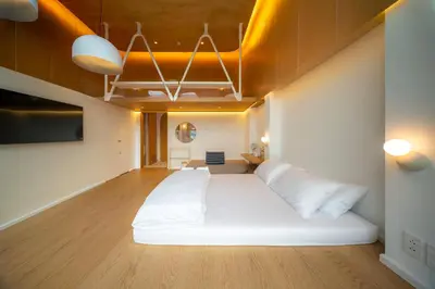 a large white bed in a room with wooden floors at Vaeh Viean Silom in Bangkok